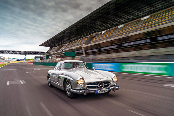 Silver Mercedes Benz 300sl Gullwing racing on a track