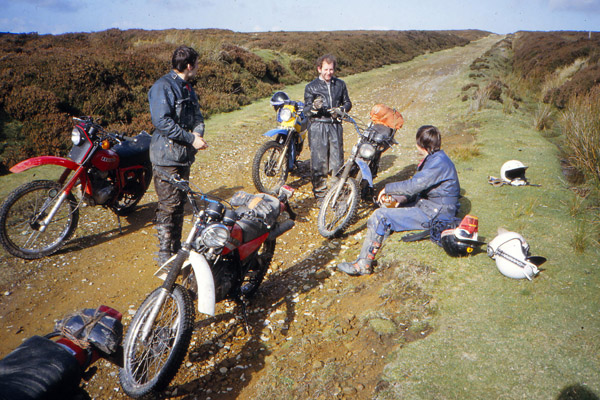 A photo of a group of friends sitting on moorland with classic motorbikes