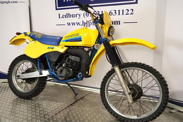 A yellow Suzuki against a white wall