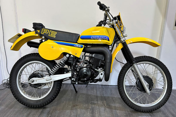 A yellow Suzuki bike against a white wall