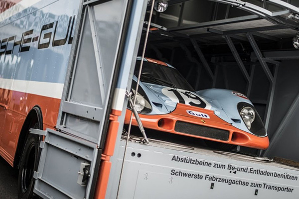 Light Blue And Orange Number 19 Porsche 917K Racing Carrying A Cage In The Back Of A Truck