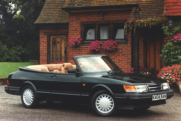 Black Saab 900 convertible beside an old home with lots of potted flowers