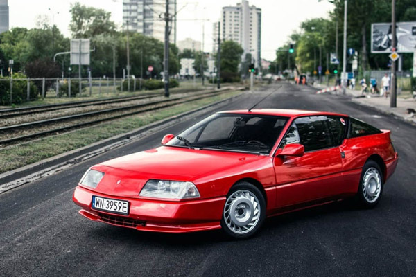 Red Renault Alpine on a city street with high rise buildings in the background