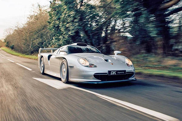 Silver Porsche 911 Gt 1 driving on a country road